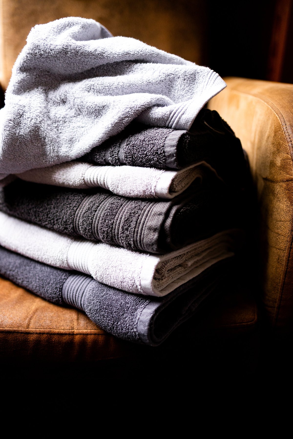 Soft gray and white folded towels resting on a cozy armchair